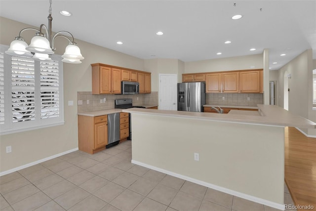 kitchen with decorative light fixtures, a center island with sink, decorative backsplash, and appliances with stainless steel finishes