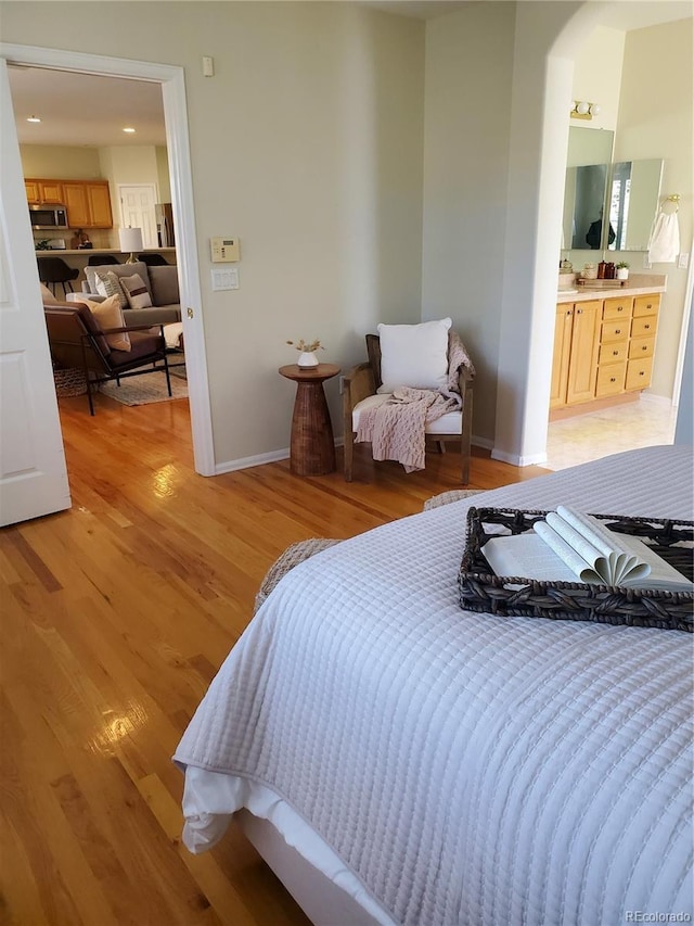 bedroom featuring ensuite bath and light hardwood / wood-style floors