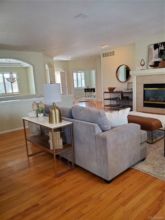 living room featuring a notable chandelier, a fireplace, and light hardwood / wood-style flooring