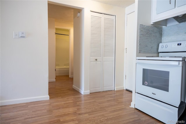 1302 S Parker Rd Unit 134, Denver, CO 80231 - kitchen with white electric range oven, backsplash, light wood-type flooring, white cabinetry, and under cabinet range hood