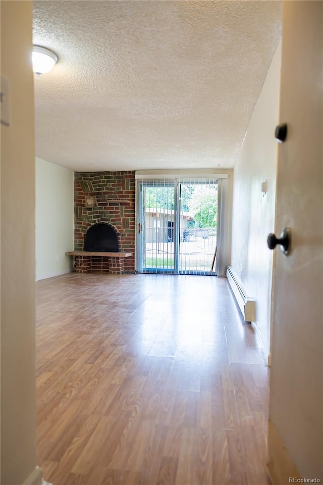 1302 S Parker Rd Unit 134, Denver, CO 80231 - unfurnished living room featuring baseboard heating, a textured ceiling, wood finished floors, and a fireplace