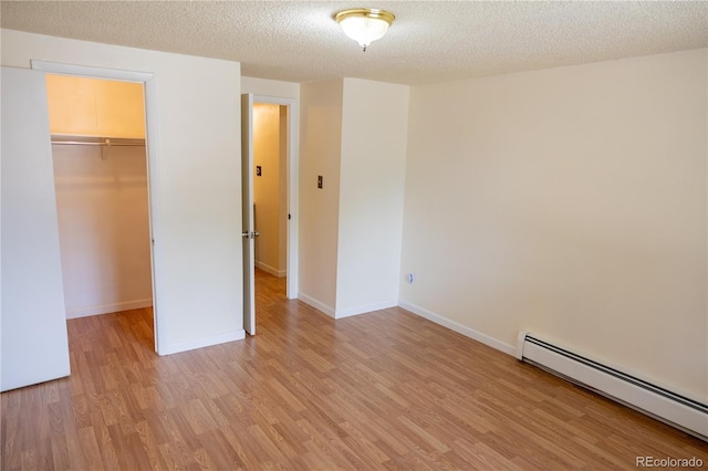 1302 S Parker Rd Unit 134, Denver, CO 80231 - unfurnished bedroom featuring a baseboard radiator, light wood-type flooring, a spacious closet, a textured ceiling, and a closet