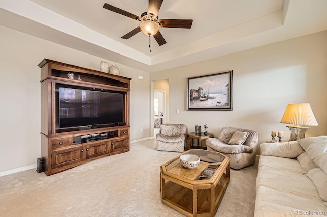 carpeted living area with baseboards, ceiling fan, and a tray ceiling
