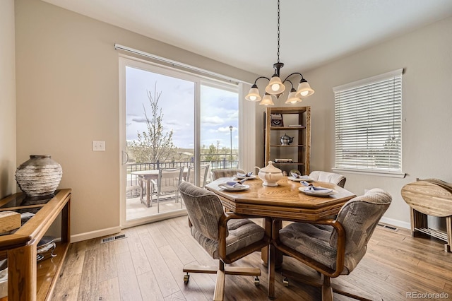 dining space with baseboards, light wood finished floors, a chandelier, and a wealth of natural light