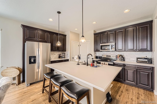 kitchen with light countertops, decorative backsplash, stainless steel appliances, and light wood finished floors