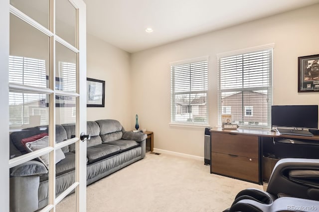 home office with baseboards, plenty of natural light, visible vents, and light colored carpet