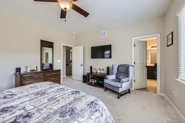 bedroom with a ceiling fan, light colored carpet, visible vents, baseboards, and ensuite bathroom