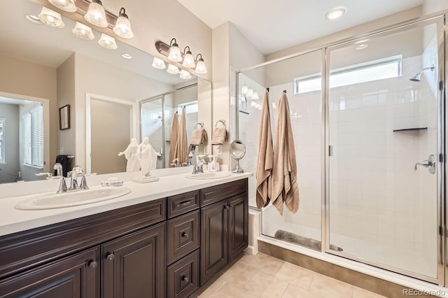 bathroom featuring tile patterned flooring, a sink, double vanity, and a shower stall