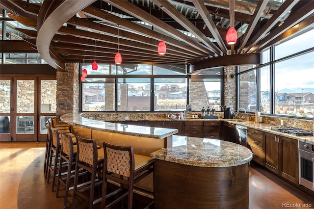 bar with stainless steel dishwasher, oven, gas cooktop, a sink, and hanging light fixtures