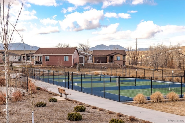 view of tennis court featuring fence, a mountain view, and a residential view