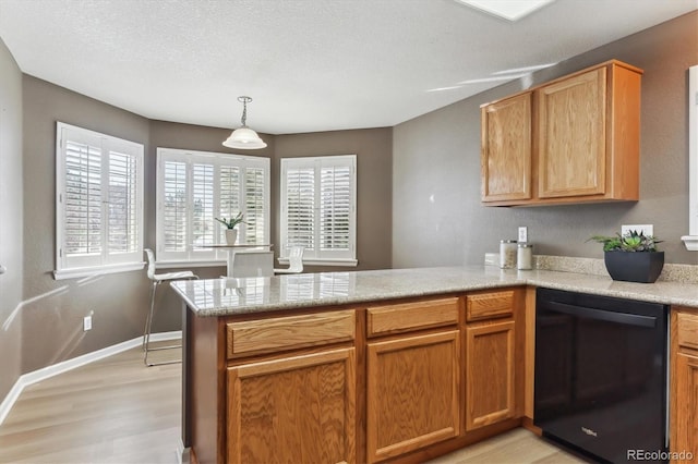 kitchen with dishwasher, hanging light fixtures, light hardwood / wood-style floors, a textured ceiling, and kitchen peninsula