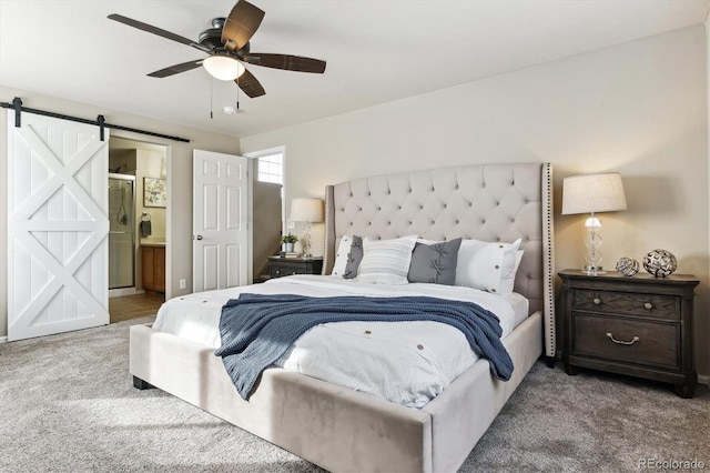 bedroom with connected bathroom, carpet floors, a barn door, and ceiling fan