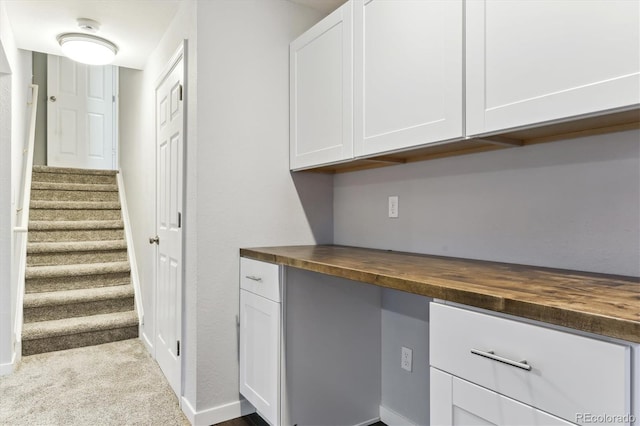 interior space with white cabinetry, light carpet, and butcher block countertops