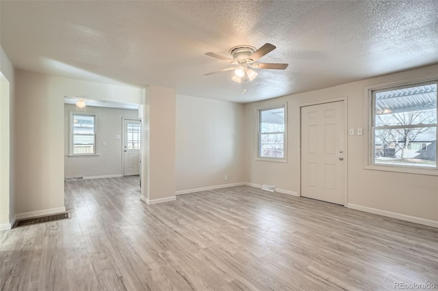 interior space with ceiling fan, a textured ceiling, a wealth of natural light, and light hardwood / wood-style flooring