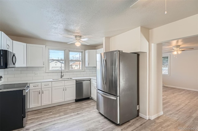 kitchen with sink, white cabinets, light wood-type flooring, and appliances with stainless steel finishes