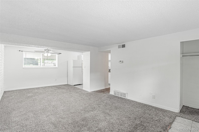 carpeted empty room with ceiling fan and a textured ceiling