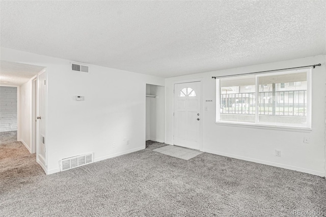 entrance foyer with a textured ceiling and carpet floors