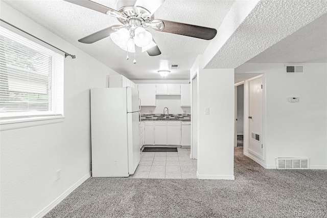 kitchen with light carpet, white cabinets, a textured ceiling, sink, and white appliances