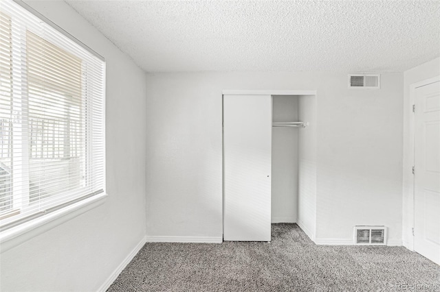 unfurnished bedroom with carpet, a textured ceiling, and a closet