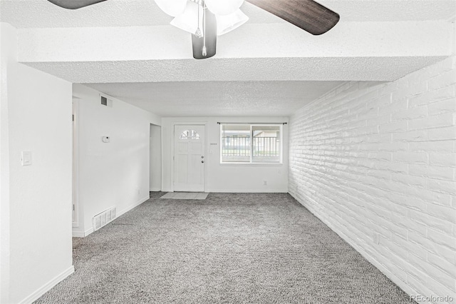 spare room featuring brick wall, a textured ceiling, carpet flooring, and ceiling fan