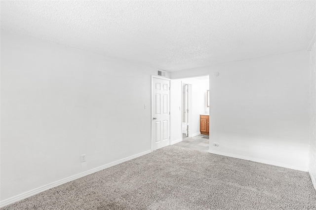 carpeted empty room featuring a textured ceiling