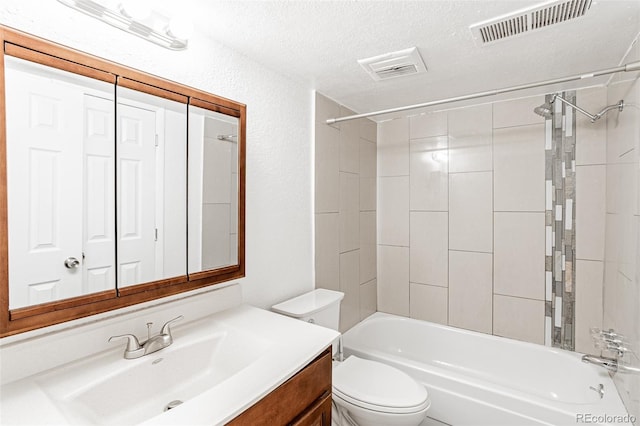 full bathroom with toilet, tiled shower / bath combo, vanity, and a textured ceiling