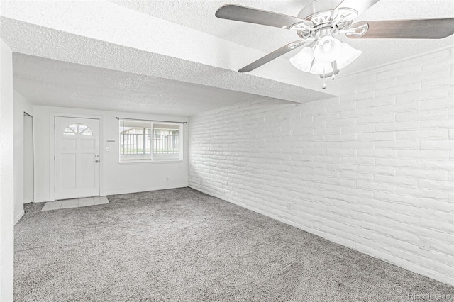 foyer entrance featuring ceiling fan, brick wall, carpet, and a textured ceiling