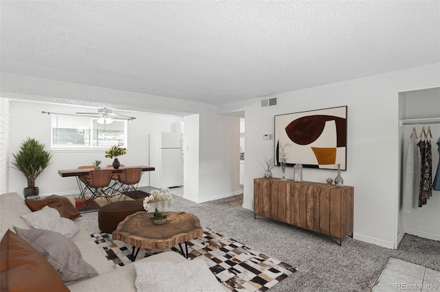 living room with ceiling fan, a textured ceiling, and light colored carpet