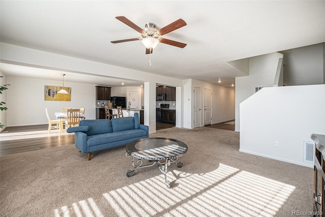 carpeted living room featuring ceiling fan