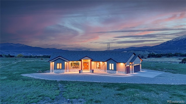 view of front of house with a yard, a mountain view, driveway, and an attached garage