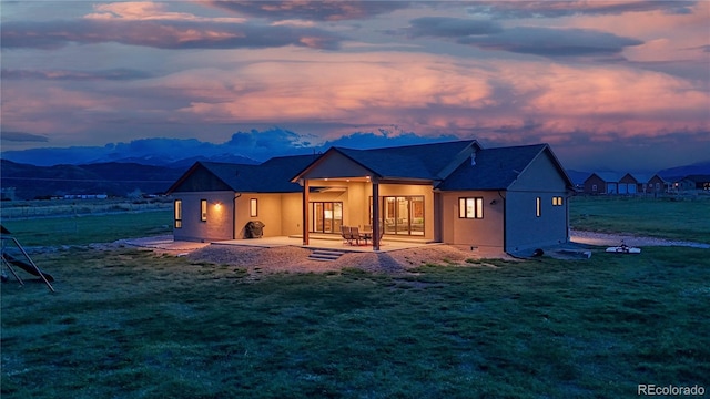 view of front facade featuring a patio, a front yard, a mountain view, and a ceiling fan