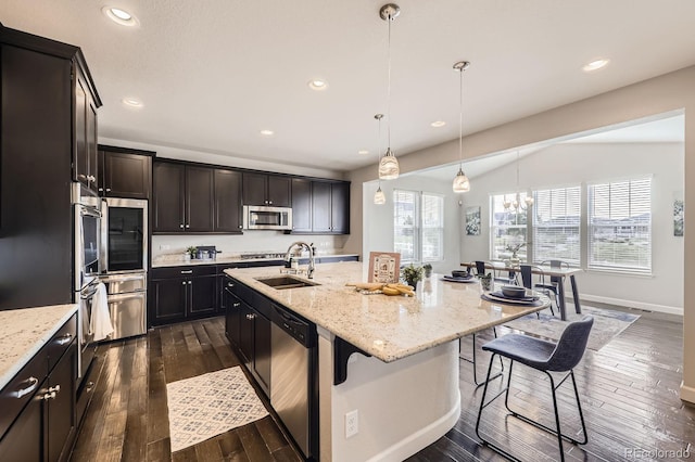 kitchen with stainless steel appliances, a sink, a kitchen breakfast bar, recessed lighting, and light stone countertops