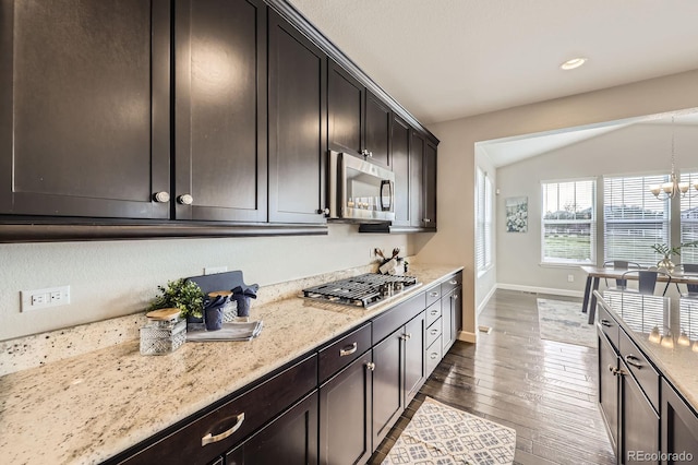 kitchen featuring stainless steel appliances, wood finished floors, vaulted ceiling, light stone countertops, and baseboards