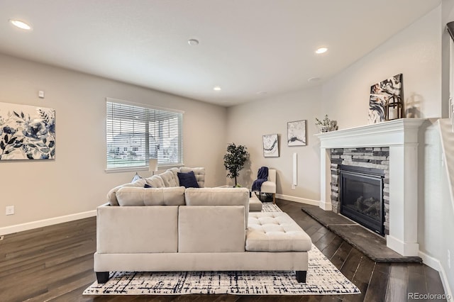 living area featuring a stone fireplace, dark wood-type flooring, baseboards, and recessed lighting