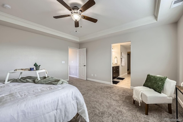 bedroom featuring a raised ceiling, crown molding, light carpet, baseboards, and ensuite bath