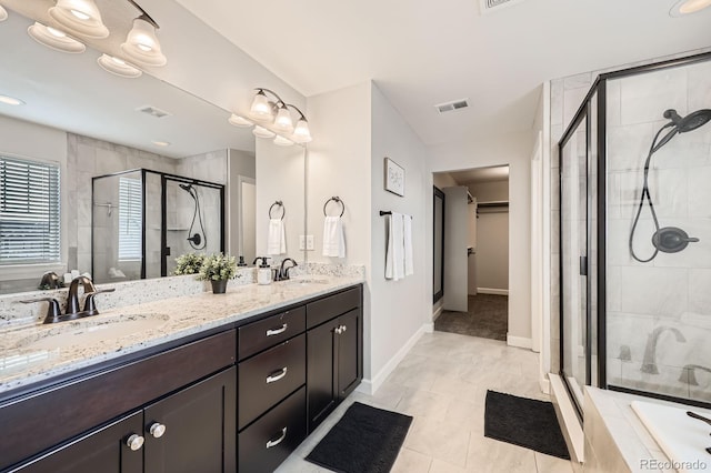 full bath featuring a shower stall, double vanity, baseboards, and a spacious closet