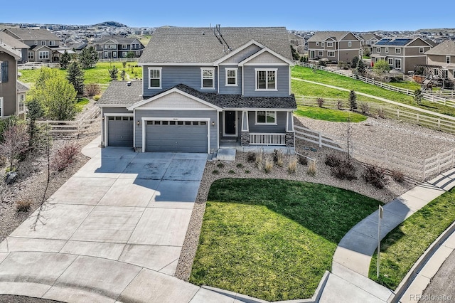 view of front of property featuring a residential view, a garage, driveway, and covered porch