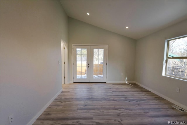 spare room featuring light wood-type flooring, high vaulted ceiling, and french doors