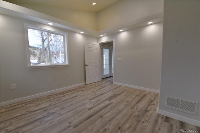 unfurnished room featuring french doors, light wood-type flooring, and high vaulted ceiling