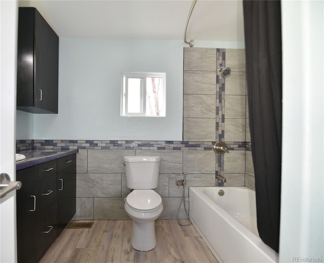 full bathroom with bathtub / shower combination, vanity, wood-type flooring, tile walls, and toilet