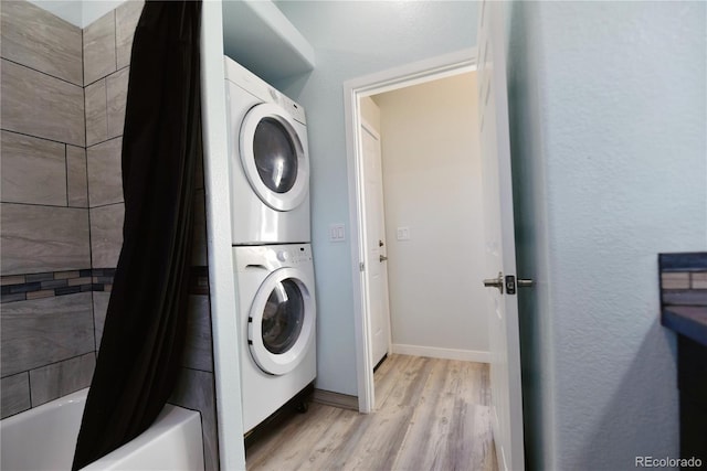 clothes washing area with light hardwood / wood-style flooring and stacked washer and clothes dryer