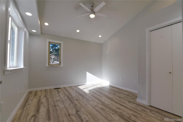 unfurnished bedroom featuring ceiling fan, light hardwood / wood-style floors, lofted ceiling, and a closet