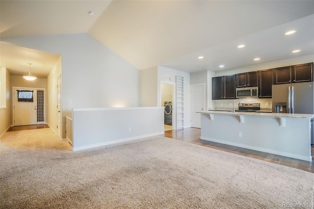 kitchen with light carpet, washer / clothes dryer, appliances with stainless steel finishes, and a breakfast bar