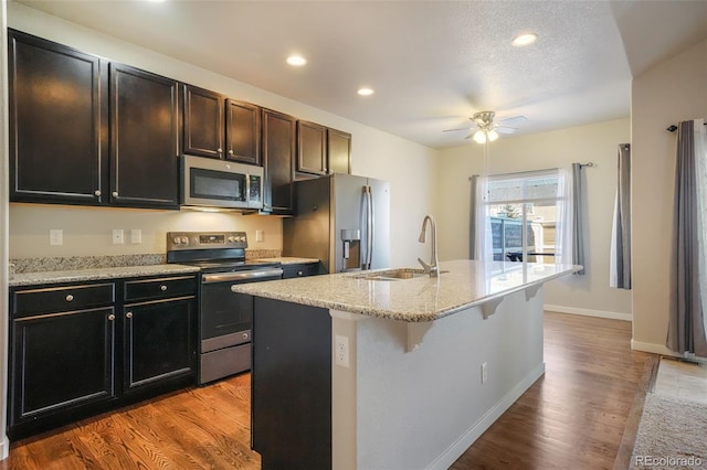 kitchen with a kitchen bar, a center island with sink, stainless steel appliances, light hardwood / wood-style flooring, and sink