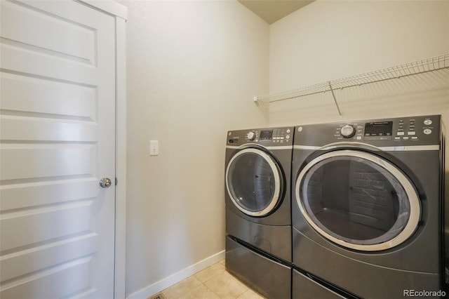 clothes washing area featuring light tile patterned floors and washing machine and dryer