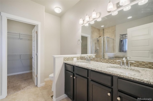 bathroom with toilet, tasteful backsplash, tile patterned flooring, walk in shower, and vanity