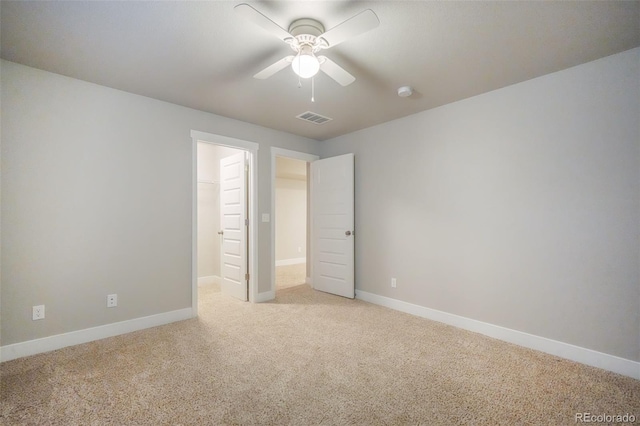 unfurnished bedroom featuring ceiling fan, light colored carpet, a closet, and a spacious closet