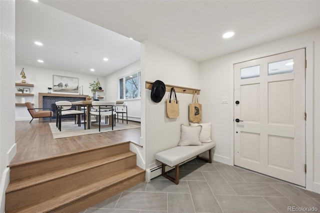 tiled foyer entrance featuring a baseboard radiator, a fireplace, and recessed lighting