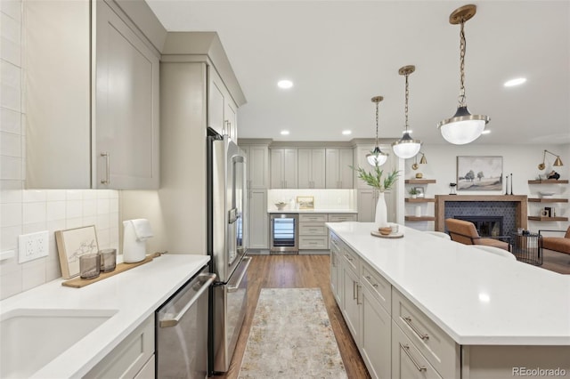 kitchen with recessed lighting, beverage cooler, stainless steel appliances, wood finished floors, and a kitchen island