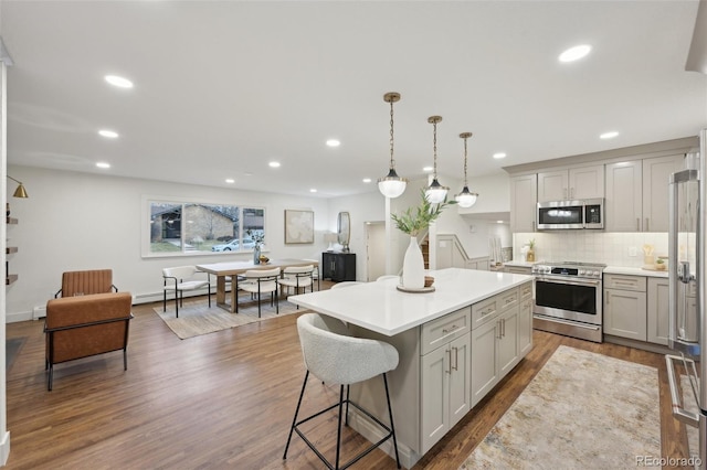 kitchen with dark wood finished floors, a kitchen island, stainless steel appliances, and backsplash